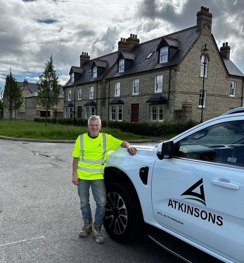 ATKINSONS tradesman with pickup outside new-build townhouses